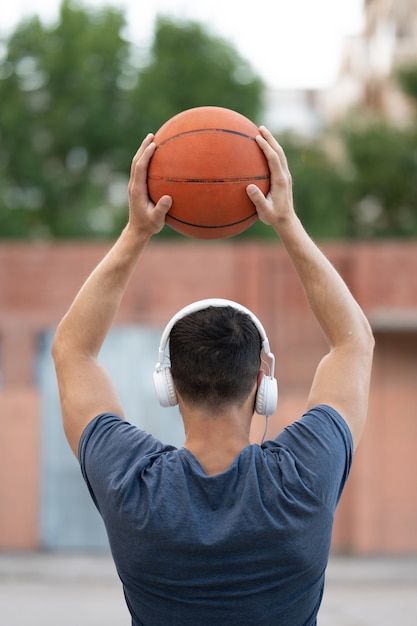 Een man speelt overdag basketbal op het erf van de straat