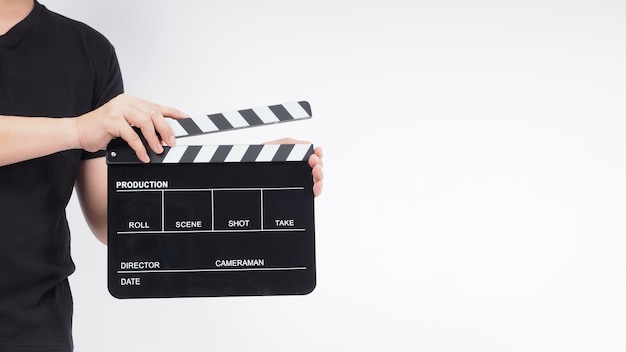 Een man staat met handen houdt zwarte Clapperboard of filmleisteen vast. het gebruikt in videoproductie, film, bioscoopindustrie. Het is een witte achtergrond.