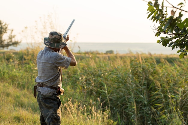 Een man staat met wapens en jachthonden het wild op te sporen