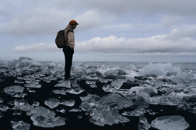 een man staat op het ijs met een rugzak en kijkt naar ijsvloeistof
