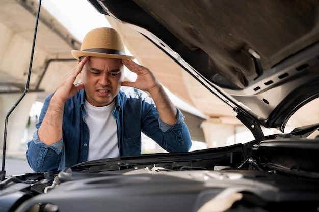 Foto een man stond gestrest voor de motorkap van een auto. zijn auto was kapot aan de kant van de weg, op zoek naar oplossingen en reparaties.