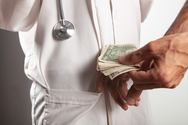 Een man stopt geld in de zak van een dokter