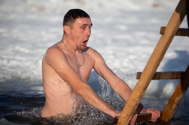 Een man stort zich in een ijsgat tijdens het winterfeest van het doopsel van jezus. een man zwemt in de winter in het ijsgat. walrussen.