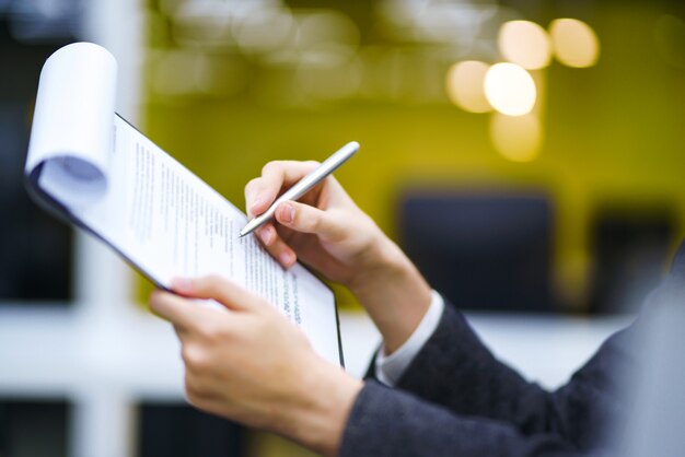 Een man tekent een contract, juridische of zakelijke overeenkomsten. Mannenhand met pen van jonge kantoormedewerker maakt aantekeningen.