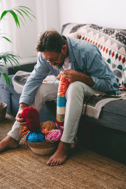 Een man thuis doet breiactiviteit alleen zittend op de bank Volwassen mannelijke mensen houden van breien zonder stress hobby en ontspannen tijd Concept van persoon en vrije tijd ontspannen levensstijl binnen