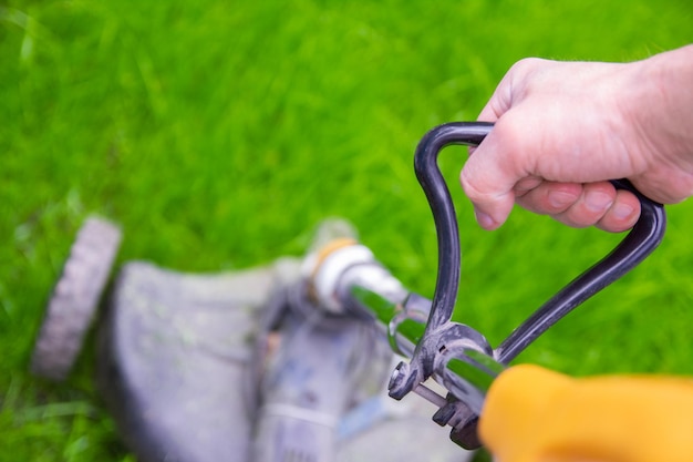 Een man trimer maait het gras op het veld op de achtergrond van het park