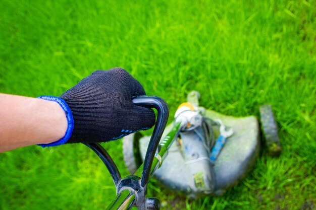 Een man trimer maait het gras op het veld op de achtergrond van het park