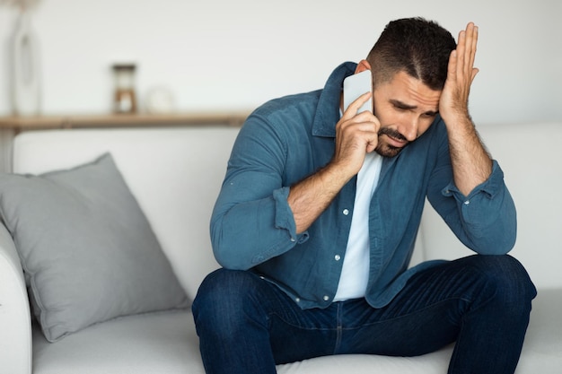 Een man van middelbare leeftijd praat aan de telefoon en vertoont stress binnen.