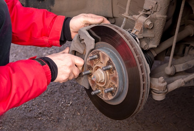 Een man vervangt de remblokken van een auto Beveiligingsdienst