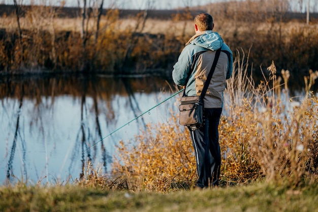 Een man visser vissen in de rivier met een hengel.