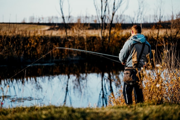 Een man visser vissen in de rivier met een hengel