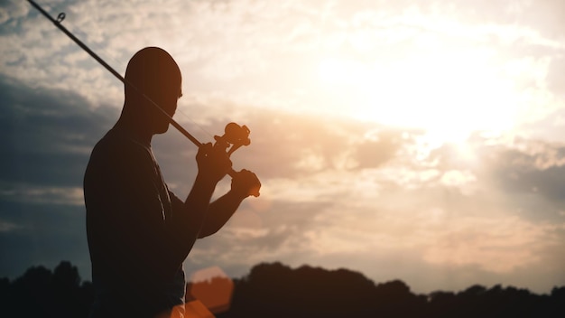 Een man vist op het meer zonsondergang rust in de natuur