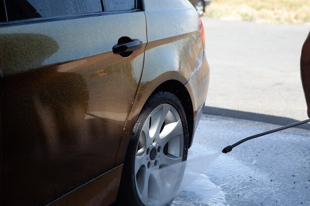 Een man wast zijn auto met water