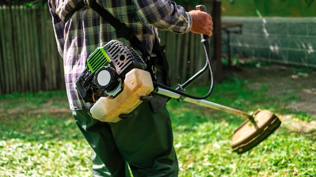 Een man werkt met een handgrasmaaier in de tuin