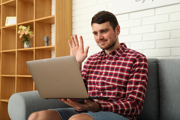 Een man werkt op een laptop op een bank