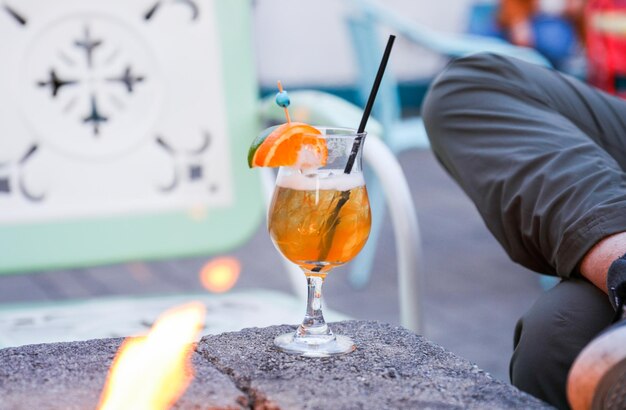 Foto een man zit aan een tafel met een cocktail en een klok aan de muur achter hem.