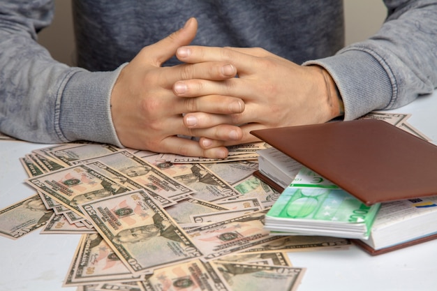 Een man zit aan een tafel vol met geld 50 dollar horizontale foto