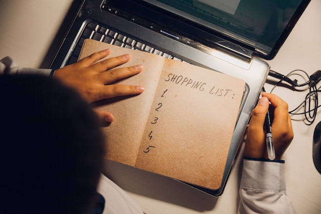 Een man zit achter een laptop en schrijft een winkelplan voor 2022. werk tot laat in de nacht op internet.