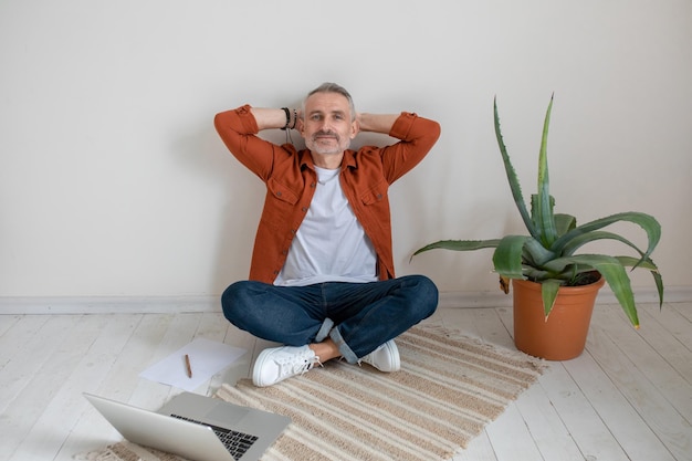 Een man zit op de grond met zijn benen over elkaar en rust uit van zijn werk