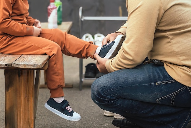 Een man zorgt voor en zorgt voor zijn dochtertje en helpt haar haar sneakers aan te trekken