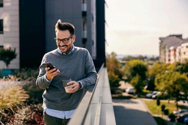 Een manager in smart casual drinkt koffie en typt berichten aan de telefoon in het centrum