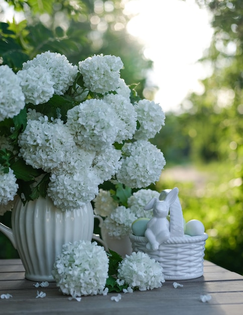 Foto een mand met eieren en een vaas met witte bloemen op een tafel in de tuin lente paasstilleven