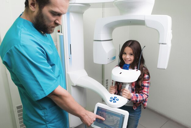 Een mannelijke arts maakt een röntgenfoto van de kaak van het meisje.
