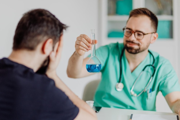 Een mannelijke arts zit tegenover een bureau van de patiënt en bespreekt medicijnen