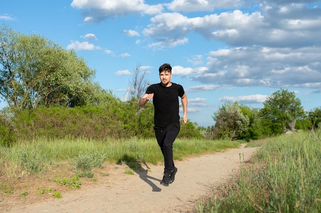 Een mannelijke atleet rent in de natuur tegen de lucht