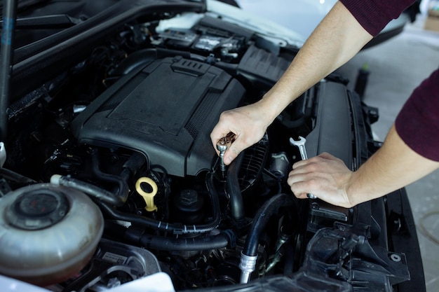 Een mannelijke automech inspecteert de motor van de auto. Autoservice en autoreparatie.