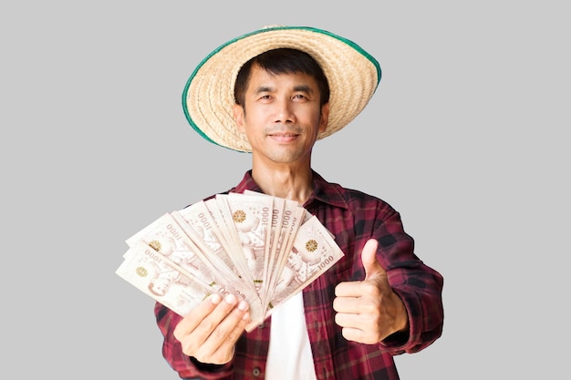 Een mannelijke Aziatische boer draagt een rood shirt staande bedrijf bankbiljetten Een half lichaam schot Geïsoleerde uitknippad afbeelding