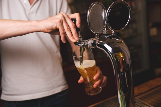 Een mannelijke barman giet een glas bier uit een kraan