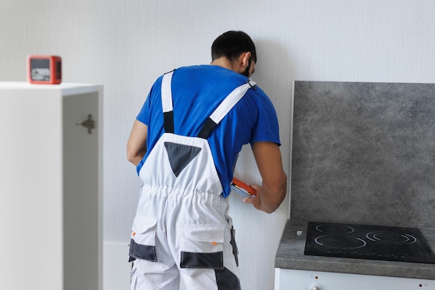 Foto een mannelijke bouwvakker kleeft een wandpaneel aan de muur met behulp van vloeibare spijkers