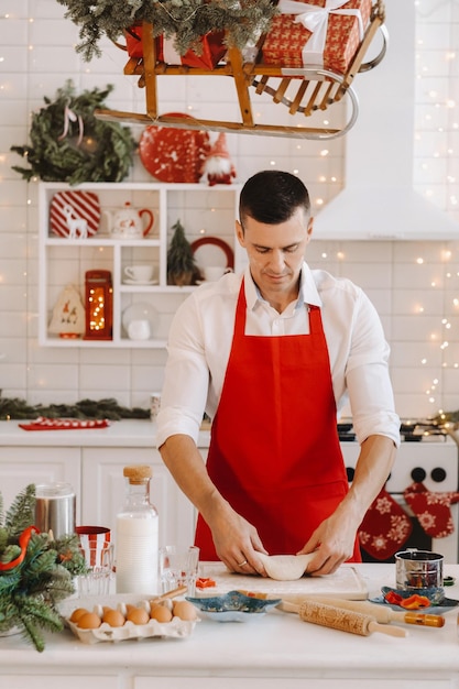 Een mannelijke chef-kok bereidt deeg in de kerstkeuken voor het nieuwe jaar.