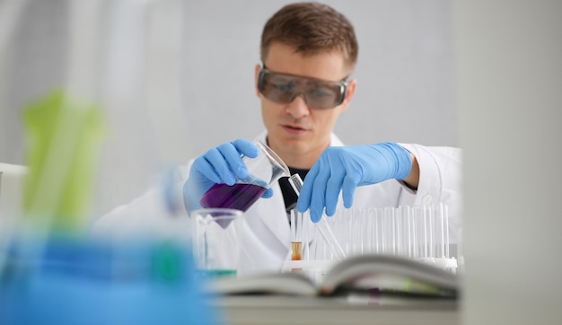 Een mannelijke chemicus houdt een proefbuis van glas vast