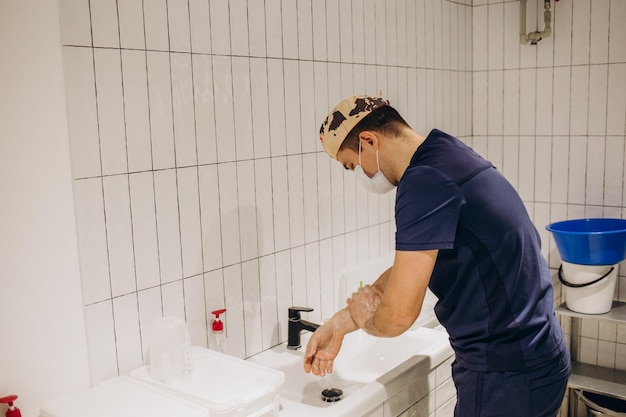 Een mannelijke chirurg in de sanitaire ruimte van een ziekenhuis wast zijn handen voor de operatie De arts bereidt zich voor op een chirurgische ingreep en desinfecteert zijn handen voor de behandeling