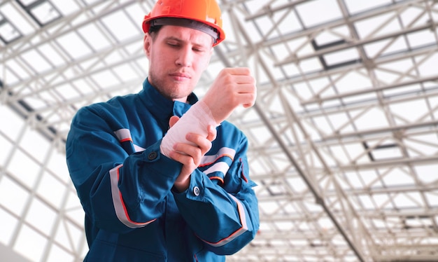 Een mannelijke fabrieksarbeider in uniform met verband, ongevalsletsel, EHBO-hulp