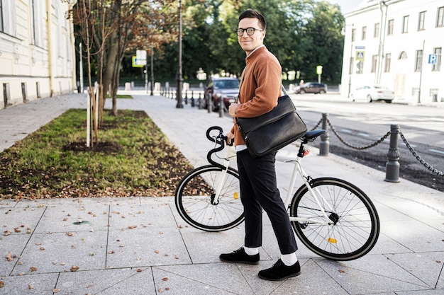 Een mannelijke fietser rijdt naar het werk met een koffer op een fiets in de stad Ecologisch vervoer