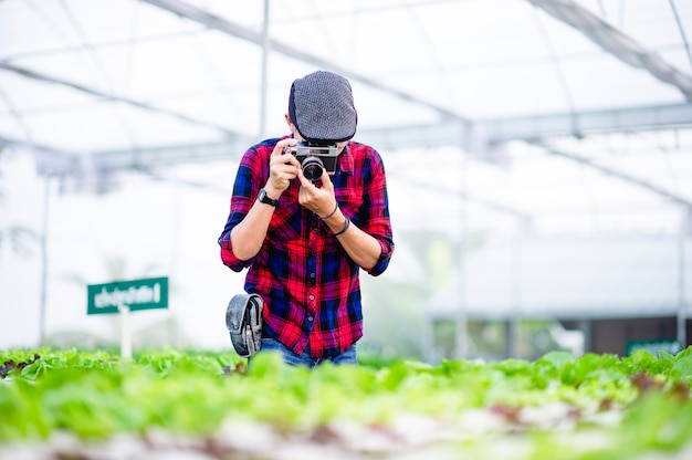 Een mannelijke fotograaf maakt foto's in zijn saladetuin en geniet van fotografie.