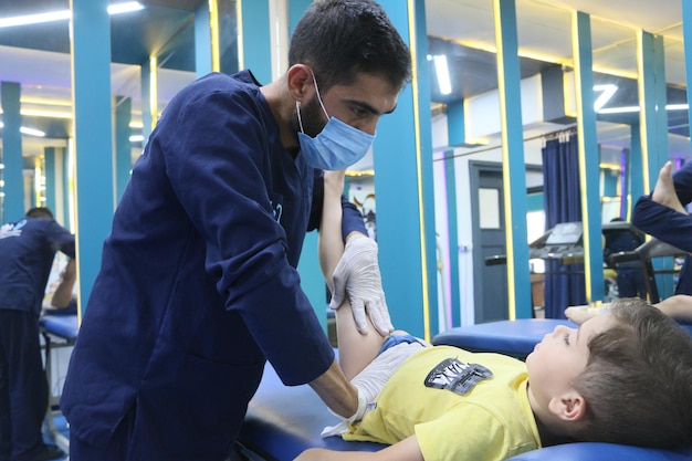 Foto een mannelijke fysiotherapeut behandelt een kind in een fysiotherapiecentrum fysiotherapie oorlogsslachtoffers