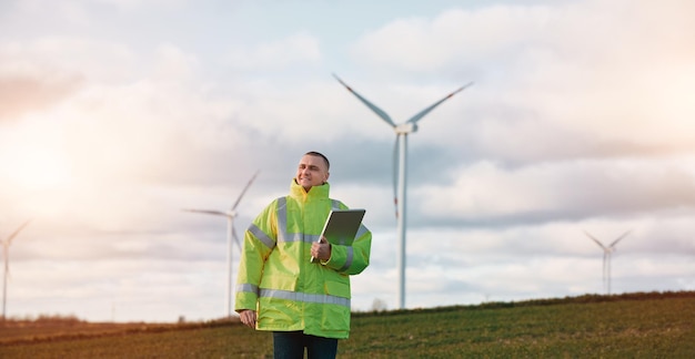 Een mannelijke ingenieur staat in een windturbineveld met een mooie hemelachtergrond Concept van duurzame toekomst