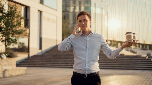 Een mannelijke manager brengt koffie naar kantoor en praat aan de telefoon