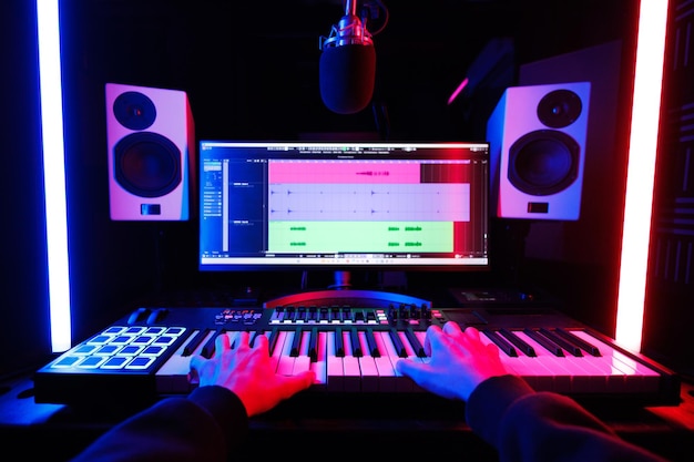 Een mannelijke muzikant die een midi-keyboardsynthesizer bespeelt in een opnamestudio, concentreerde zich op zijn handen