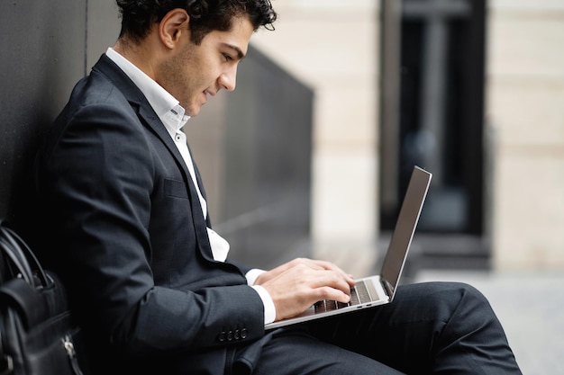 Een mannelijke ondernemer gebruikt een laptop in een pak aan het werk