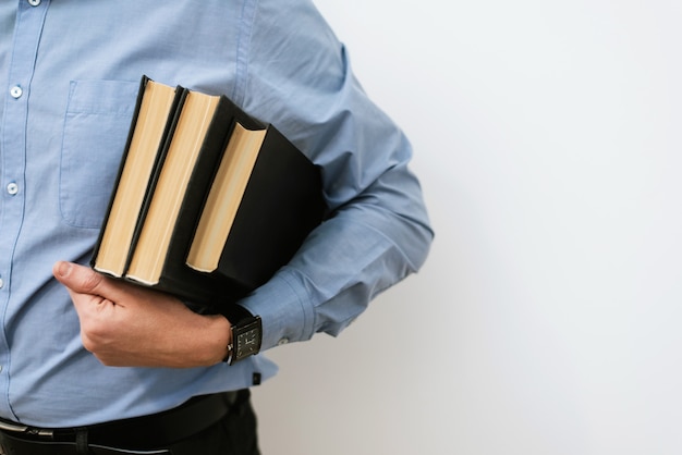 Een mannelijke student in een blauw shirt en broek broek houdt een stapel boeken. Het concept van training, zoeken naar ideeën, bedrijfsoplossingen