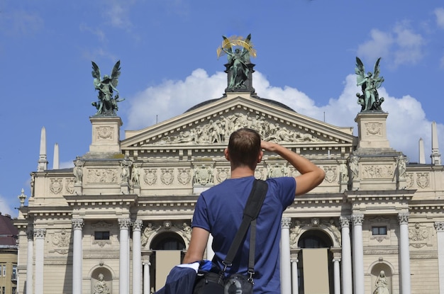 Een mannelijke toerist kijkt naar de prachtige gevel van het gebouw Lviv Opera en Ballet Theater
