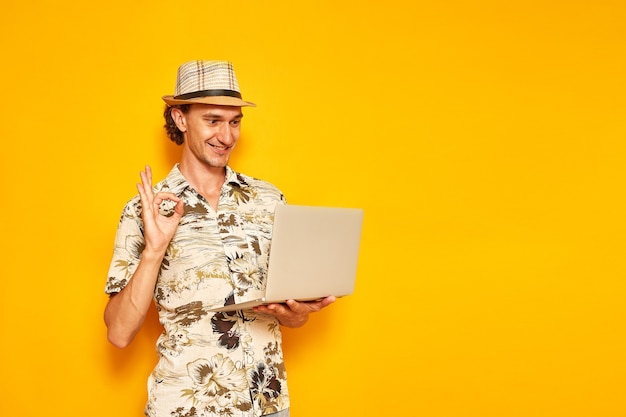 een mannelijke toerist met laptop in zijn handen verheugt zich over ontvangen bericht geïsoleerd op gele achtergrond