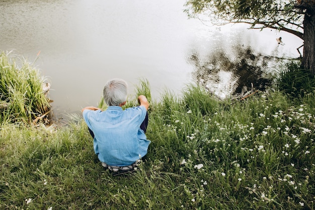 Een mannelijke visser zit aan de kust en kijkt naar het water