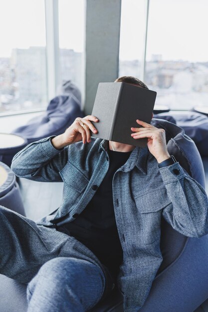 Een mannelijke zakenman in een casual pak die in een comfortabele poef rust terwijl hij werkt, een aantrekkelijke freelancer in een pak werkt op afstand en controleert aantekeningen in een notitieboekje