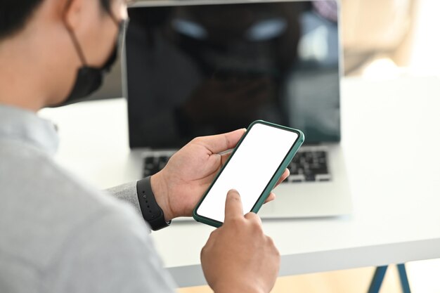 Een mannenhand die mobiele telefoon met behulp van op hwork-ruimte